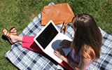 Student working on a laptop outside on a picnic blanket