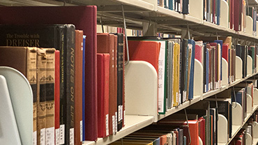 Books lining the shelves at Lauinger Library, with beige dividers and spines of every color.