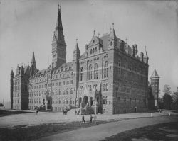 Black and white photo showing exterior of Healy Hall and students on the lawn in front of it