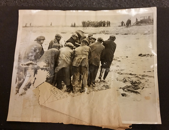 photograph of fishermen carrying an airplane engine from the sea onto shore before conservation treatment