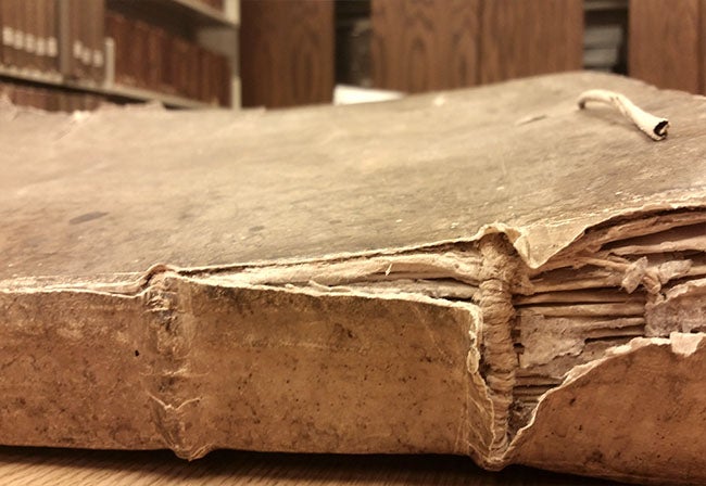 book spine with parchment covering torn before conservation treatment