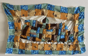 A patchwork quilt with blue, green, brown, orange, and burgandy fabrics. 