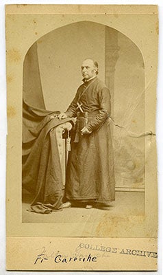 Frederick Peter Garesché, S.J. stands in his cossack with his right hand resting on an ornamental curtain, his name written in ink below the photo with the stamp of the College Archives