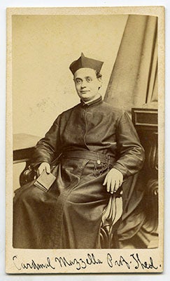 Camillus Mazzella, S.J., seated in hs cossack with a book in his right hand, his name wriiten in black ink under the photograph