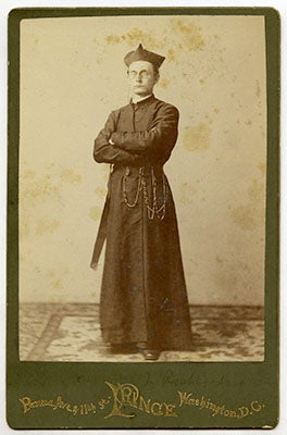 J. Havens Richards, S.J., standing in his cossack with his arms crossed and the name and address of the photography studio Prince printed below the photo