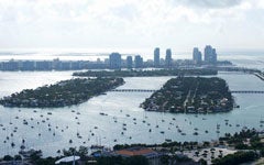 Aerial view of the Miami skyline, with the ocean, islands, and boats in the foreground.