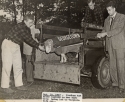 a photograph of four georgetown students surrounding an open trailer containing the fordham ram, which is wearing a blanket that reads "georgetown." a typewritten caption reads, "Oct. 10, 1947 - Fordham ram after capture in new york city, being led to virginia hide out..."