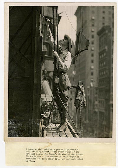 Photo of woman painting a poster on skyscraper