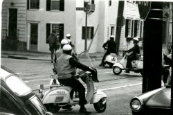 Black and white photograph of 5 police on scooters driving through the intersection of 37th and Prospect streets