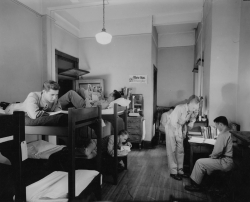 Black and white photograph of dorm room with 3 sets of bunkbeds and 6 ASTP cadets