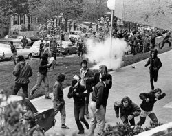 Black and white photograph showing students running away from tear gas
