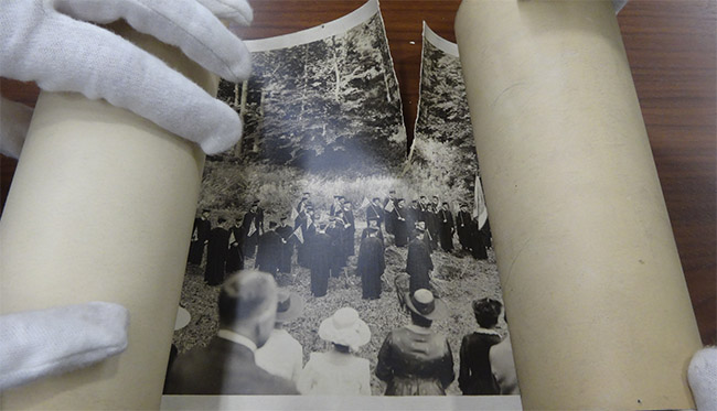 rolled brittle and torn photograph of photograph of Georgetown faculty and students in regalia holding flags and banners before conservation treatment