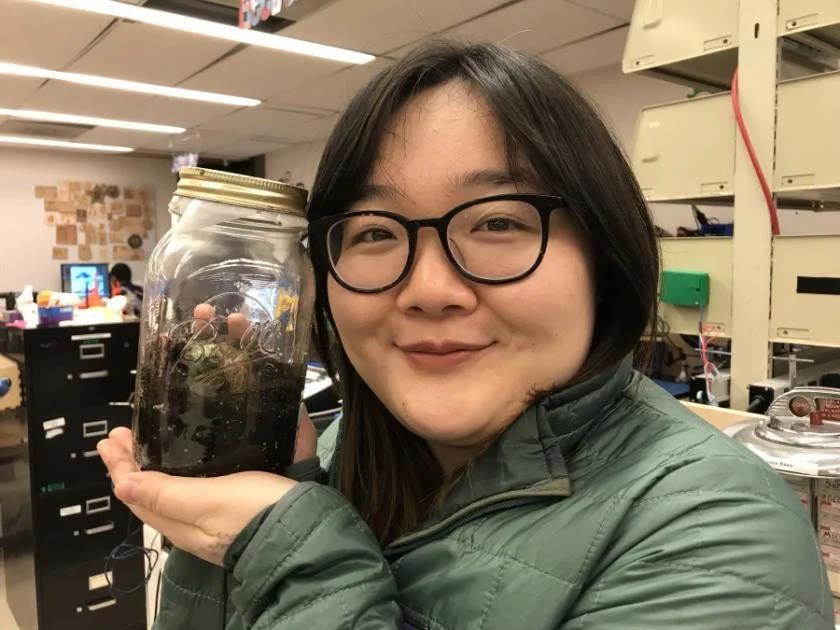 A smiling student proudly displays her completed terrarium jar in the Maker Hub