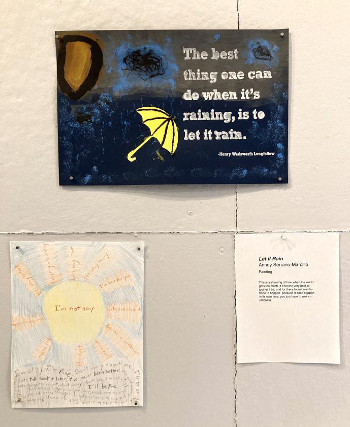 two posters set vertically on a wall, the top dark blue with a yellow umbrella, the bottom one hand drawn colored pencil of a sun