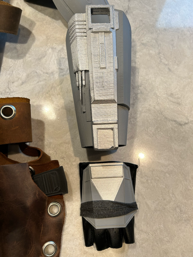 the left arm and hand 3d printed silver pieces of the mandalorian costume