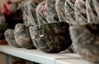 A row of army combat helmets on a shelf