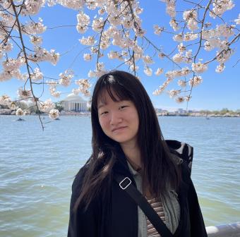 Isabella Liu poses with the tidal basin cherry blossoms and the Jefferson Memorial in the background