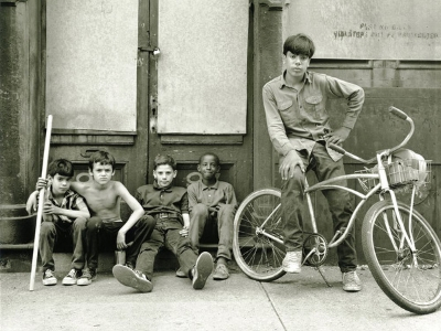 Children sitting in front of an apartment building with a bike