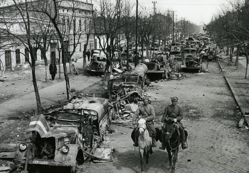 Men on horses examine damaged cars