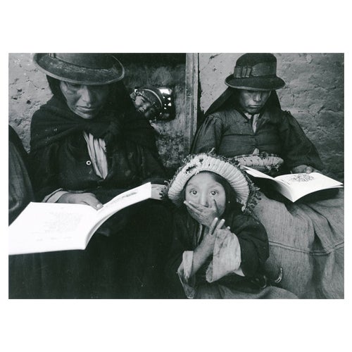 Child covering her mouth in front of two women reading